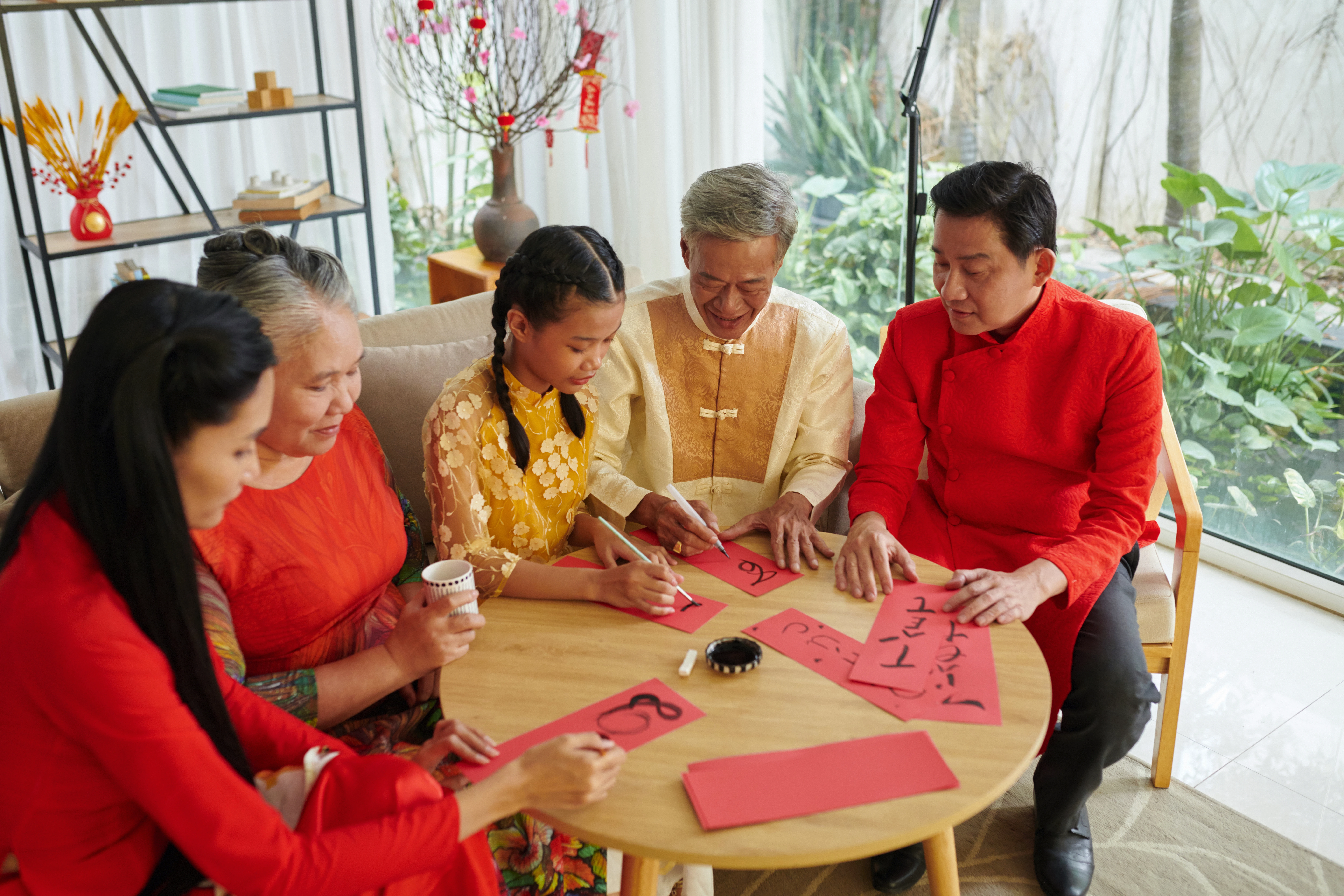 A family of three with elders writing Zhong Kai couplets signifying togetherness, love, wealth, prosperity and wholeness.