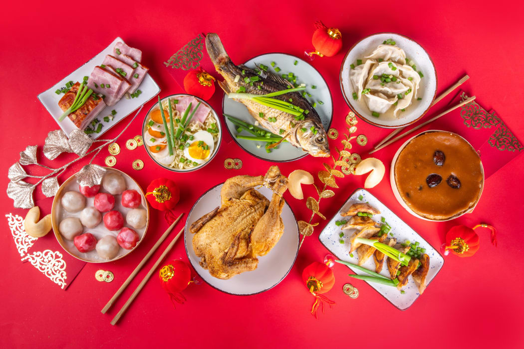 Chinese New Year feast featuring symbolic dishes served on a red table with lucky ornaments.