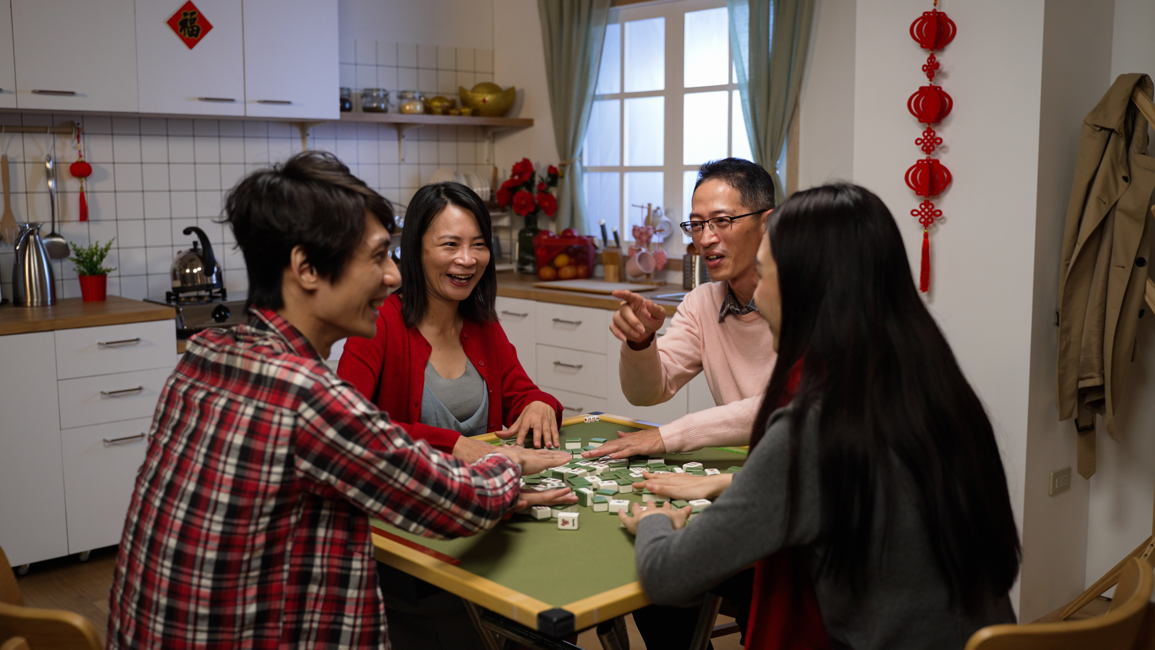 A family of 4 playing Mahjong together rekindling relationships and showing togetherness